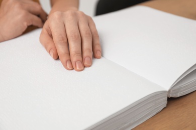 Photo of Blind woman reading book written in Braille, closeup