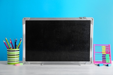 Photo of Small chalkboard and different school stationery on table