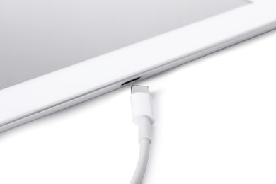 Photo of USB cable with lightning connector and tablet on white background