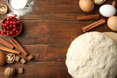 Flat lay composition with dough on wooden table, space for text. Cooking pastries