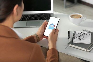 Image of Woman checking new message on mobile phone at table, closeup