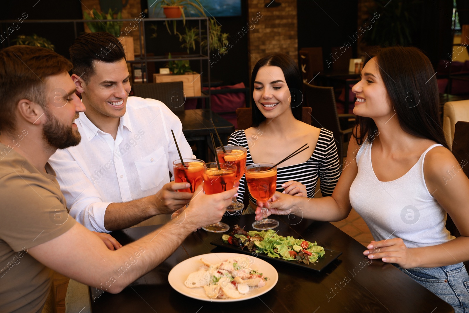 Photo of Friends with Aperol spritz cocktails resting together at restaurant