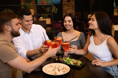 Friends with Aperol spritz cocktails resting together at restaurant