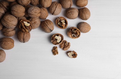 Photo of Pile of ripe walnuts on white wooden table, flat lay