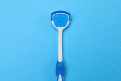 Photo of Tongue cleaner on blue background, top view