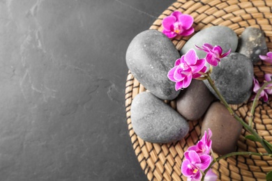 Flat lay composition with orchid flowers and spa stones on grey table. Space for text