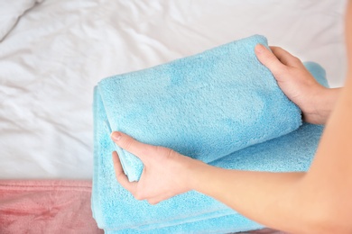 Photo of Woman folding clean towels on bed, closeup