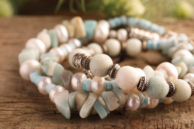 Photo of Beautiful bracelets with gemstones on wooden surface, closeup