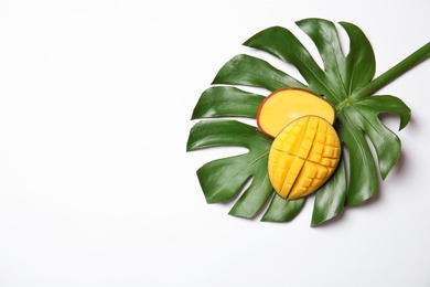 Juicy mango and green tropical leaf isolated on white, top view. Space for text