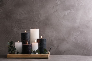 Tray with burning candles and green branches on table, space for text