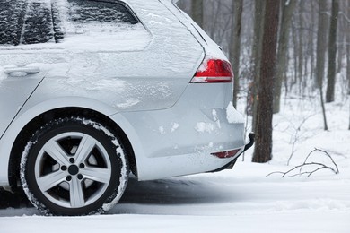 Car with winter tires on snowy road in forest