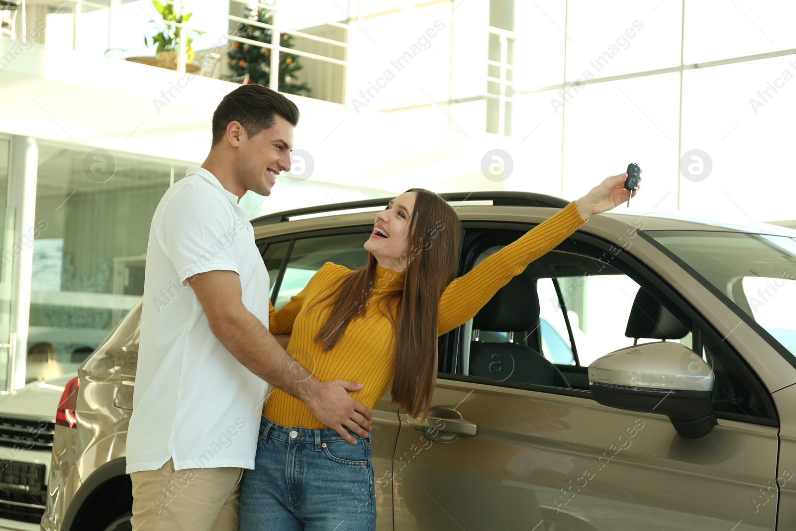 Photo of Happy couple with car key in modern auto dealership