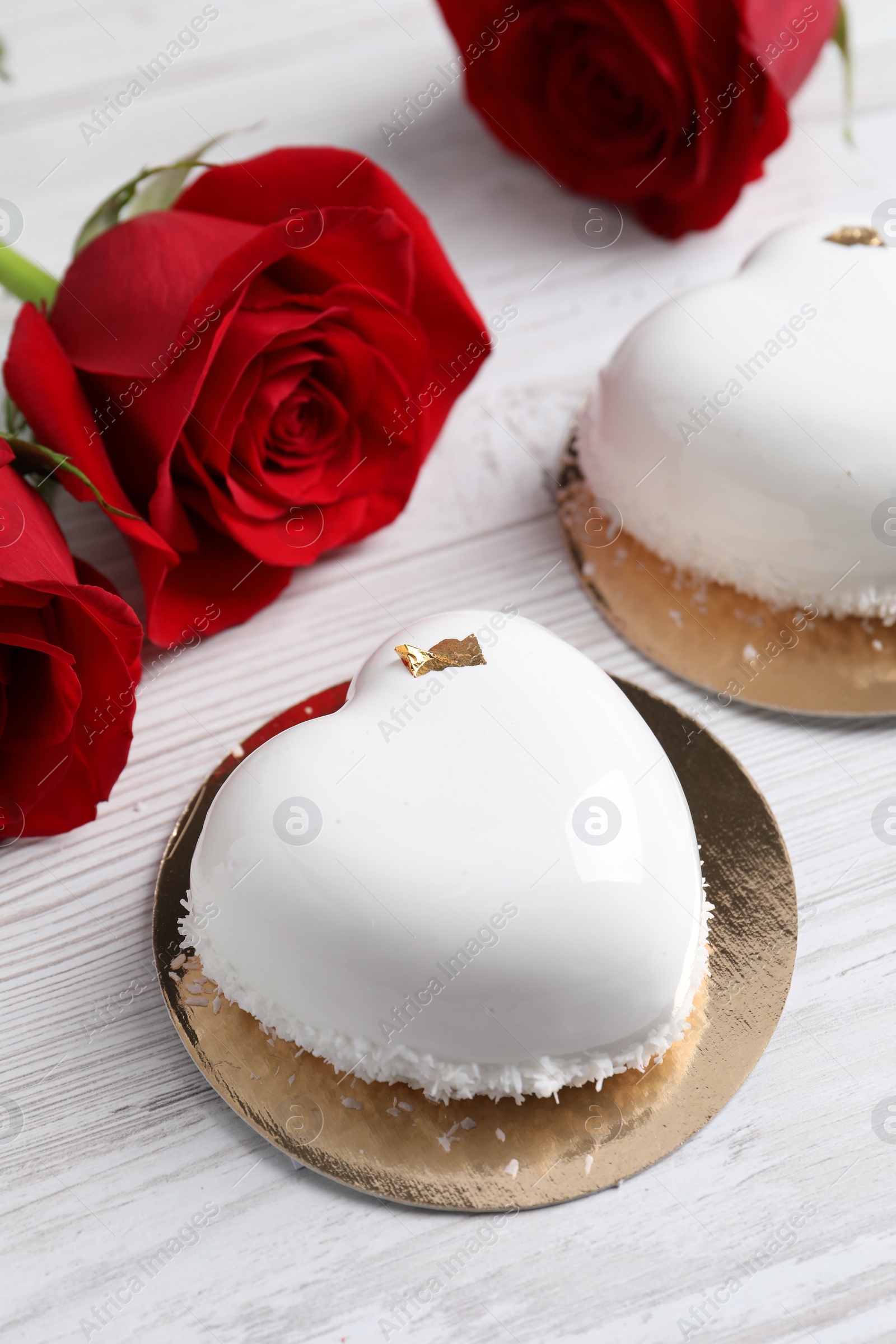 Photo of St. Valentine's Day. Delicious heart shaped cakes and roses on white wooden table