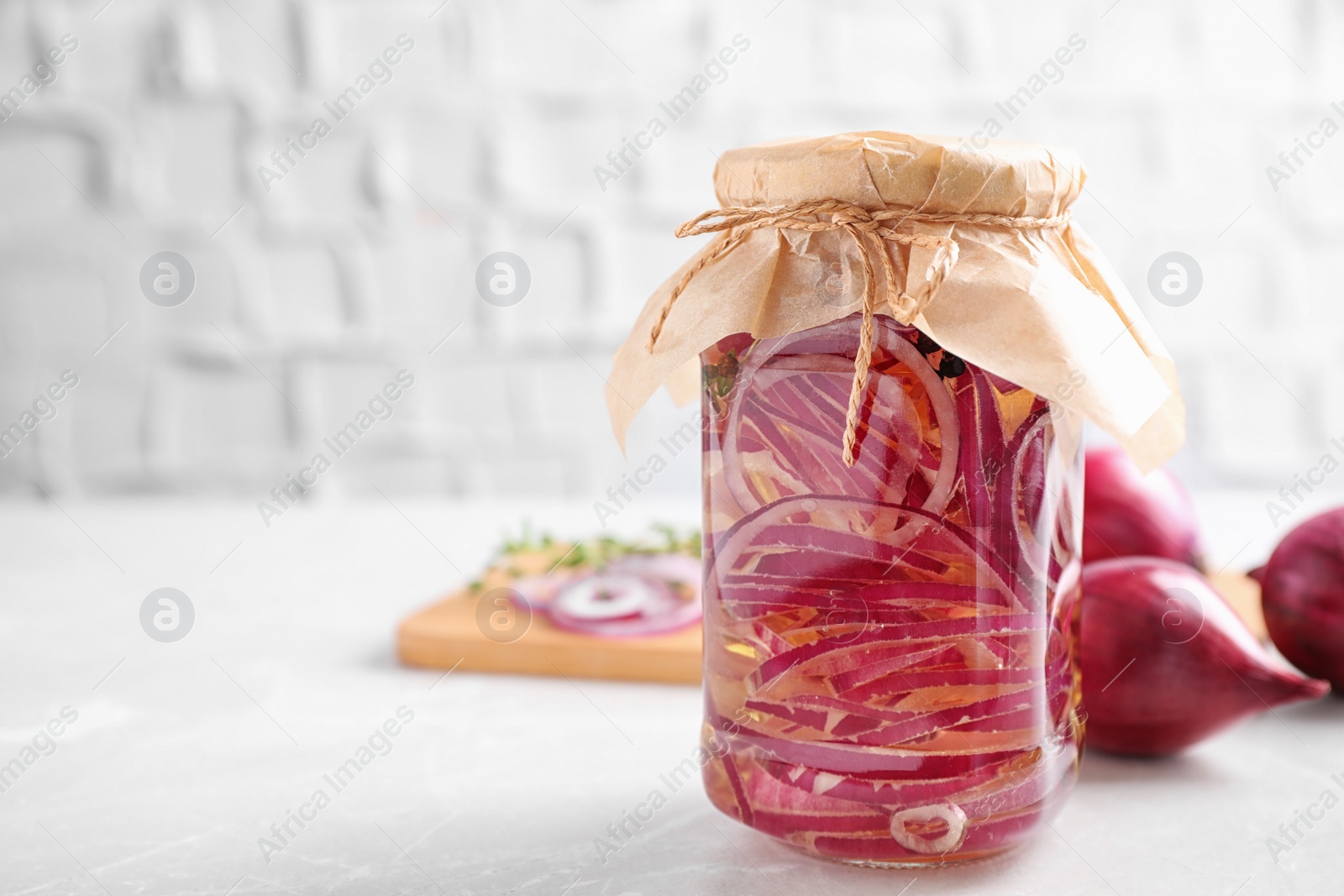 Photo of Jar of pickled onions on white table. Space for text