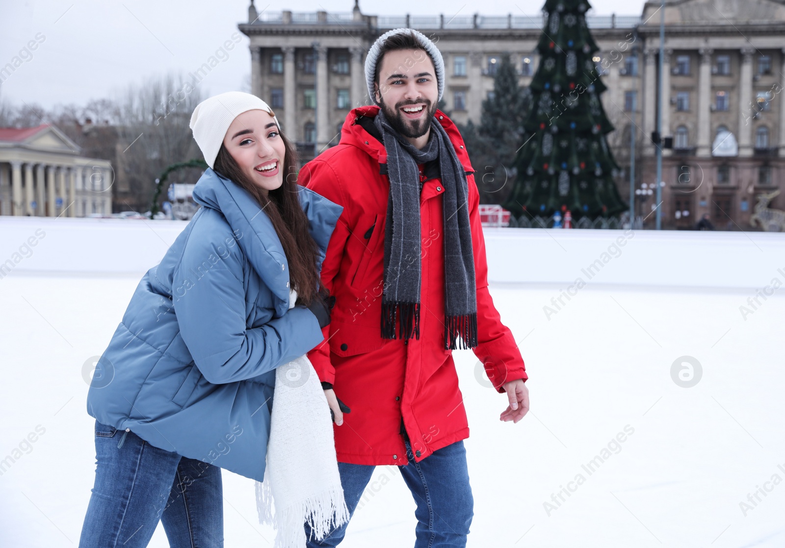 Image of Happy couple skating along ice rink outdoors. Space for text