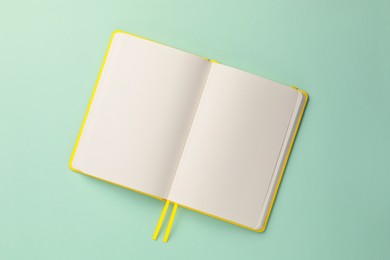 Blank notebook on turquoise background, top view