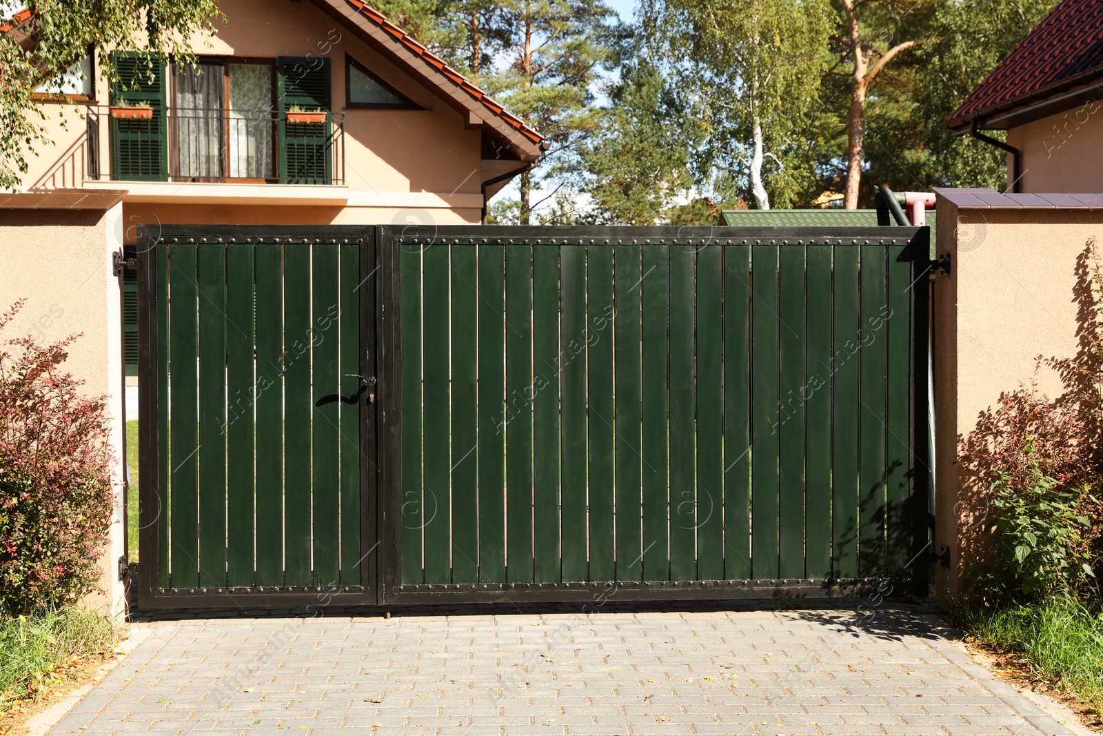 Photo of Green gates near house and trees outdoors