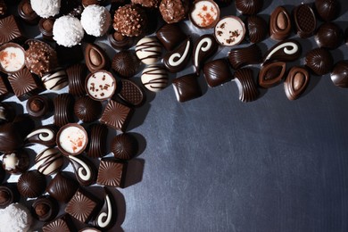 Photo of Many different delicious chocolate candies on metal surface, flat lay. Space for text