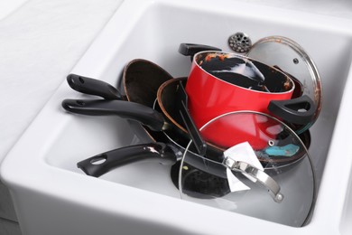 Photo of Messy pile of dirty kitchenware in sink