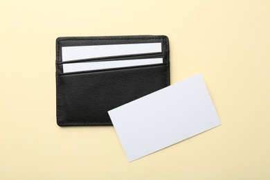 Photo of Leather business card holder with blank cards on beige background, top view