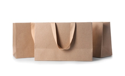 Photo of Paper shopping bags with comfortable handles on white background. Mockup for design