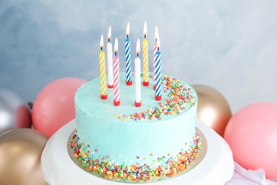 Fresh delicious birthday cake with candles near balloons on color background