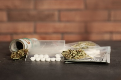 Photo of Plastic bags with pills, hemp buds and money on grey table