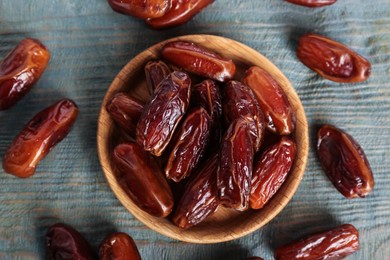 Photo of Sweet dried dates in bowl on light blue wooden table, flat lay