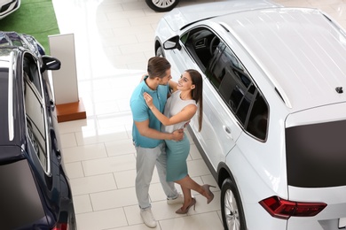 Happy couple buying new car in salon