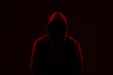 Silhouette of anonymous man on dark background, toned in red