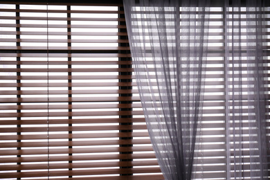 Photo of Window with beautiful curtain and blinds, closeup