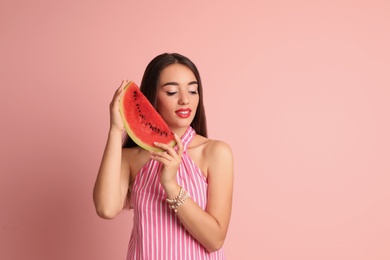 Beautiful young woman posing with watermelon on color background