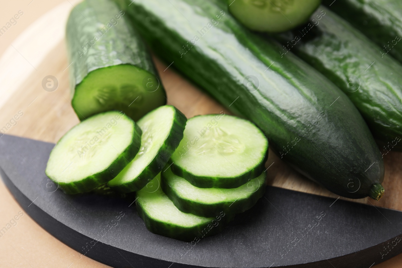 Photo of Fresh whole and cut cucumbers on beige background, closeup