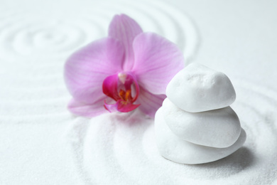 Stack of white stones and beautiful flower on sand with pattern. Zen, meditation, harmony