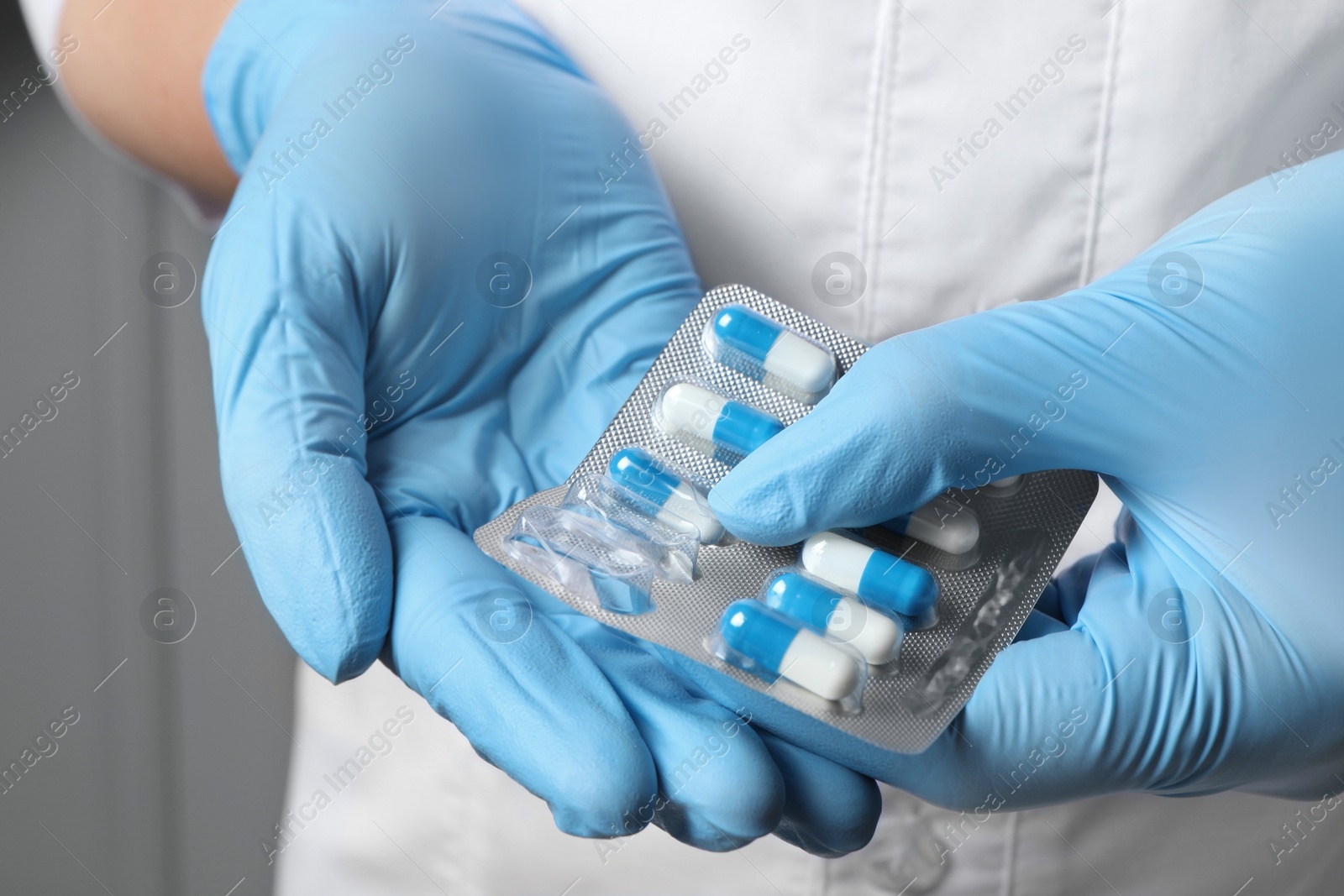 Photo of Doctor taking pill out from blister pack on grey background, closeup