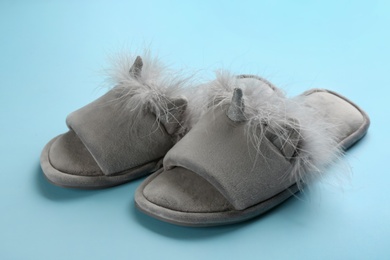 Pair of stylish soft slippers on light blue background