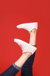 Woman in stylish sport shoes on color background