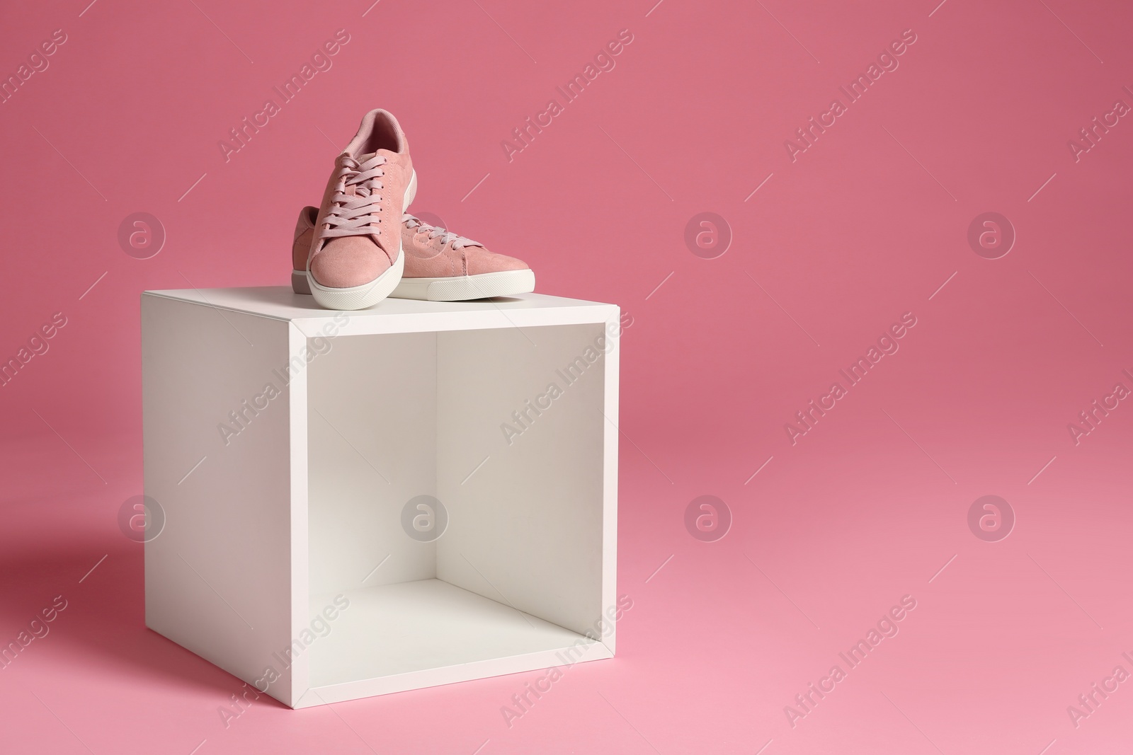 Photo of Beautiful bright stylish shoes on decorative stand against color background. Space for text