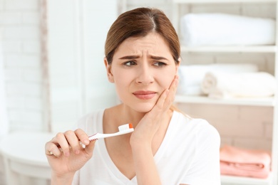 Photo of Young woman suffering from toothache indoors