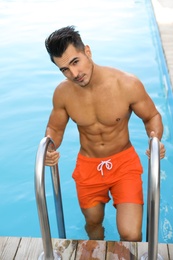 Young man getting out of outdoor pool