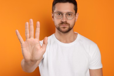 Photo of Handsome man showing stop gesture on orange background, selective focus