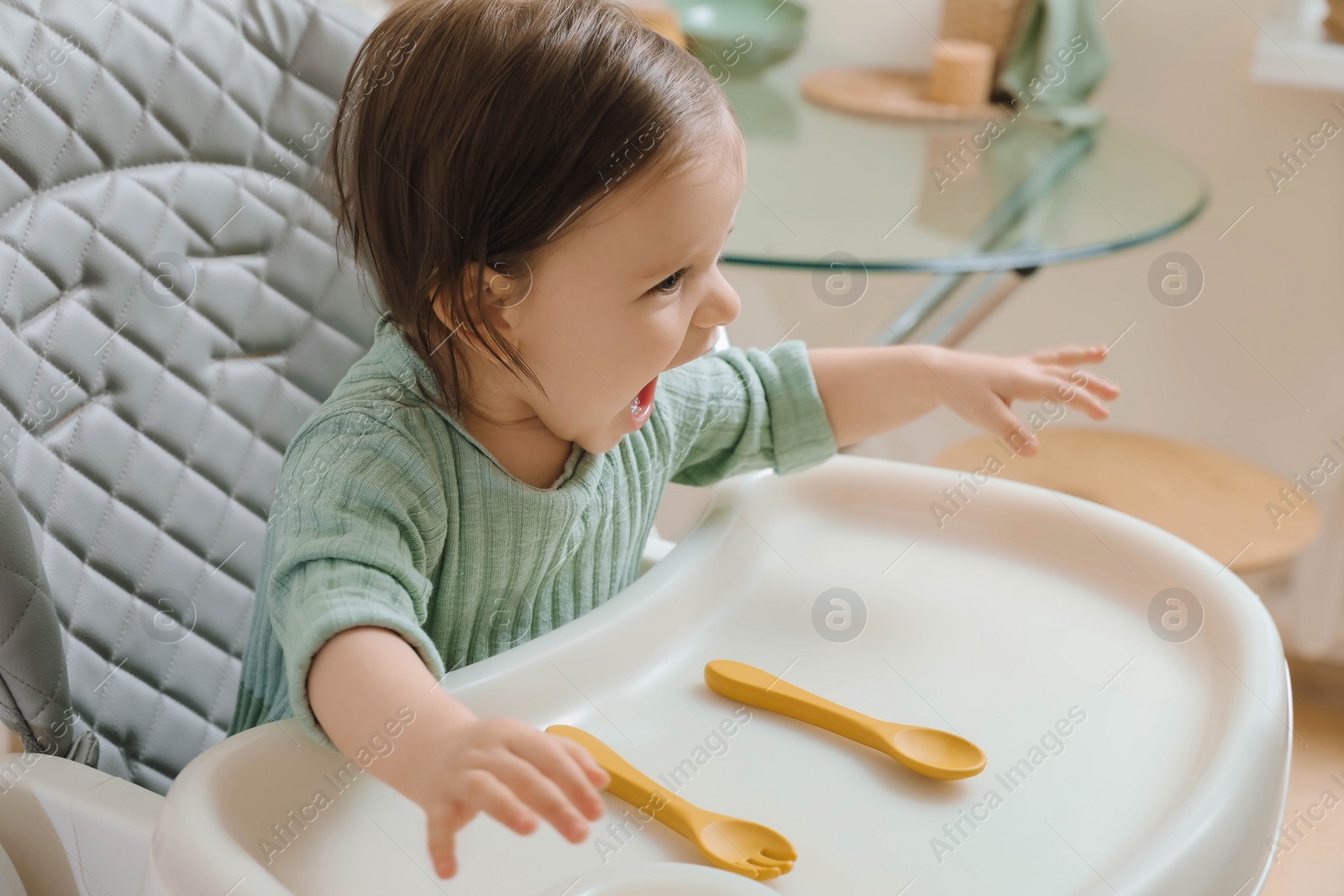 Photo of Cute little baby sitting in high chair indoors