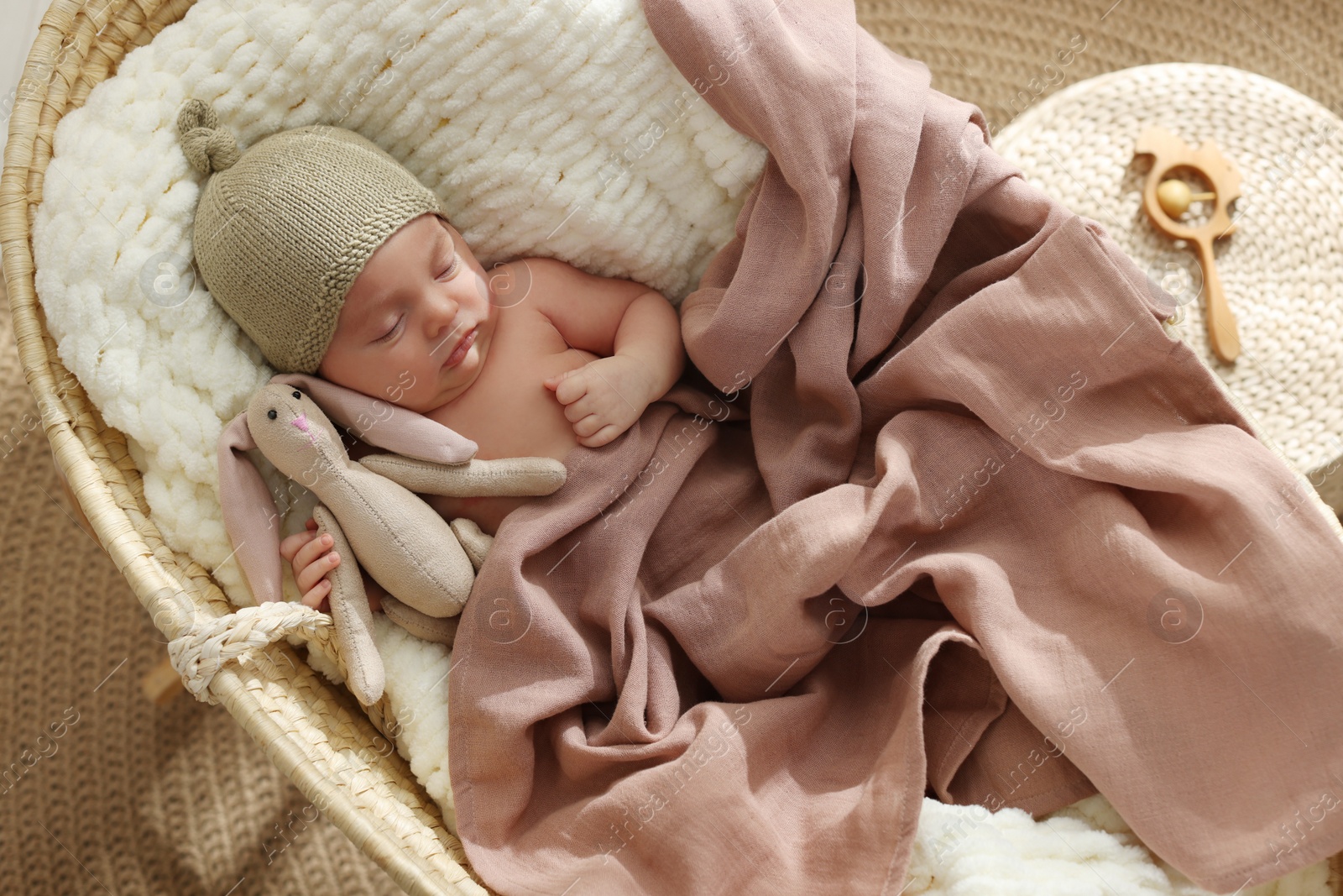 Photo of Cute newborn baby with toy bunny sleeping in cradle at home, top view