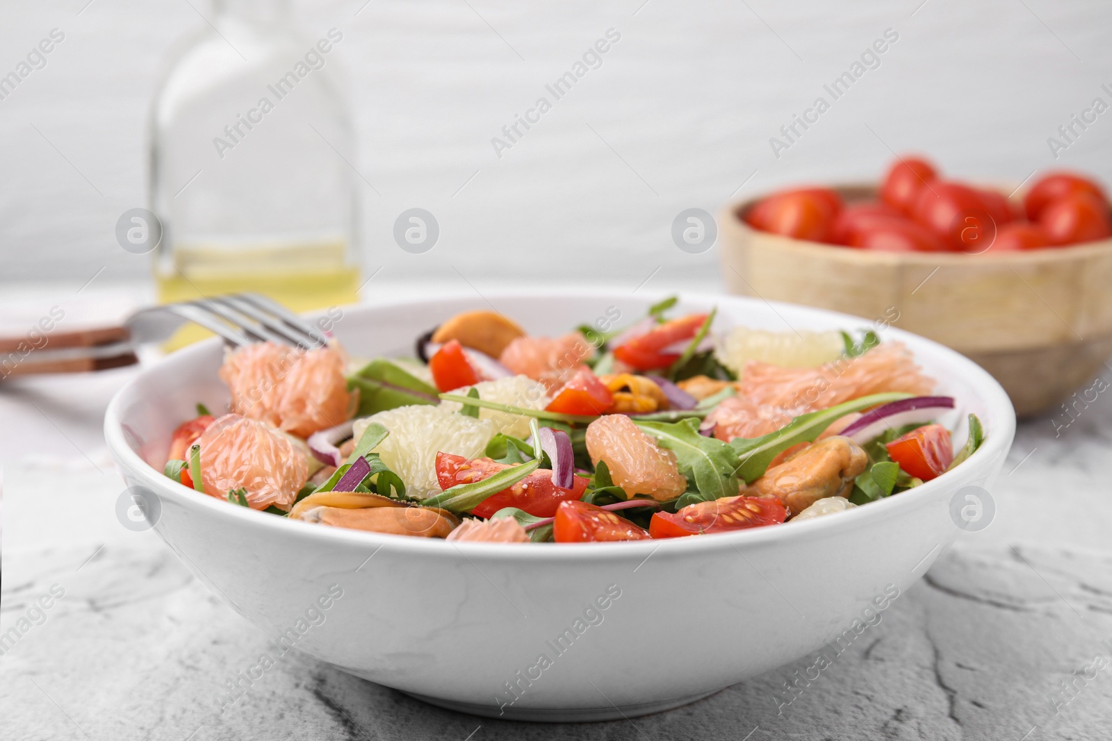 Photo of Delicious pomelo salad with tomatoes and mussels on white textured table, closeup