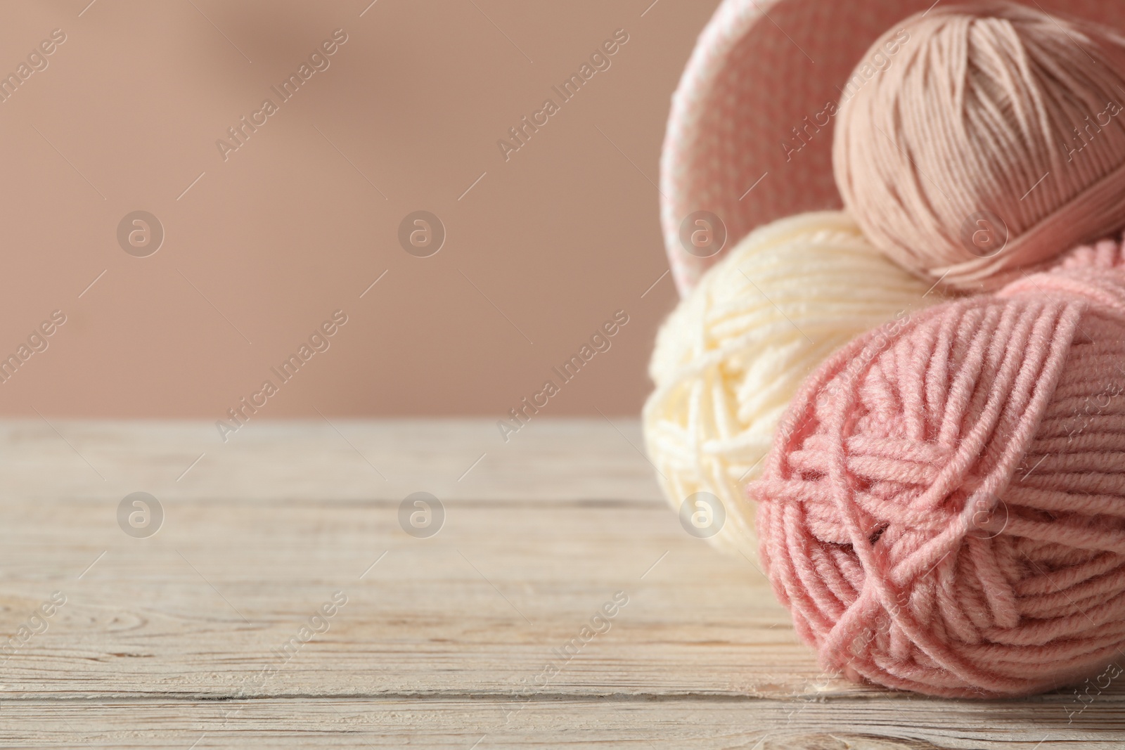 Photo of Soft woolen yarns on white table, closeup. Space for text