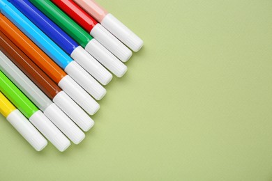 Photo of Different colorful markers on light green background, flat lay. Space for text