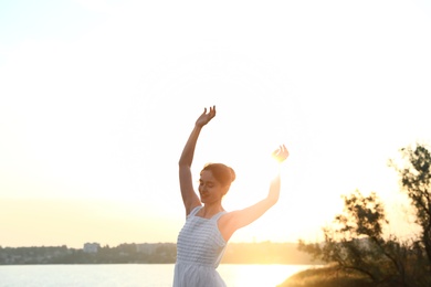 Beautiful woman enjoying nature near river. Zen and harmony