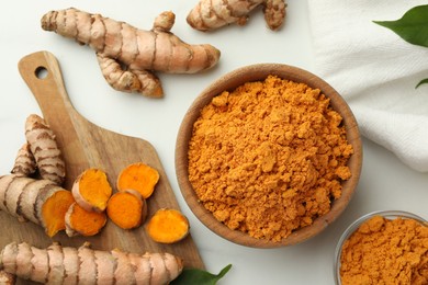 Aromatic turmeric powder and raw roots on white table, flat lay