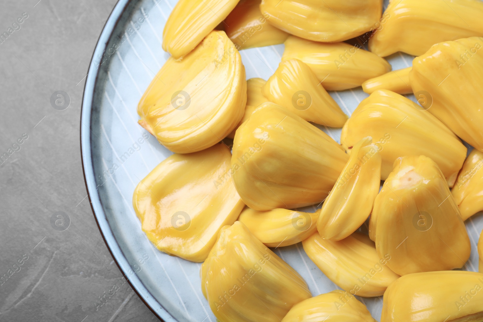 Photo of Delicious exotic jackfruit bulbs on grey table, top view