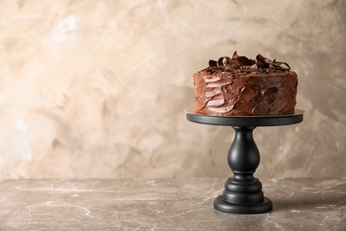 Stand with tasty homemade chocolate cake on table. Space for text